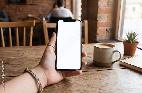 Mobile phone mockup with empty display in cozy cafe environment, coffee and work lifestyle scene