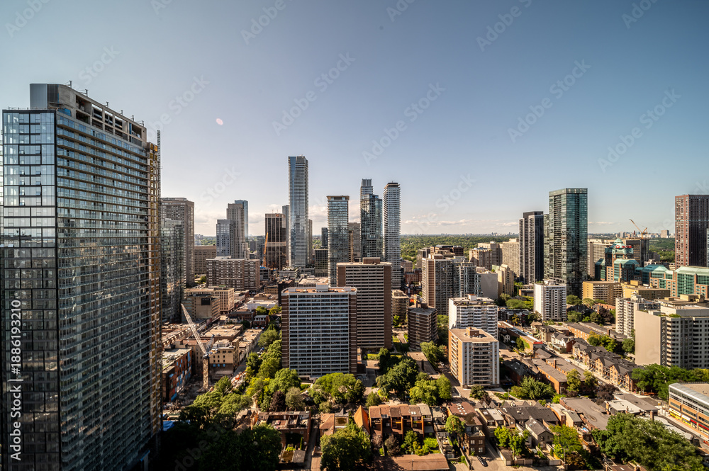 Fototapeta premium Toronto skyline panoramic aerial view of downtown skyscrapers, mixed residential buildings and tree lined streets under a clear blue sky, showing urban growth and lively city life