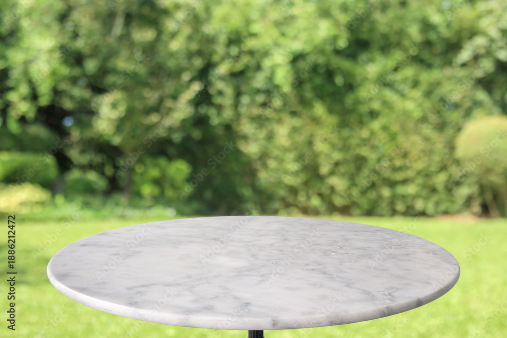 Naklejka premium Empty round marble table top with abstract blur green park garden background