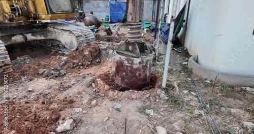 Bored piling drilling bucket and crawler tracks at a construction site.