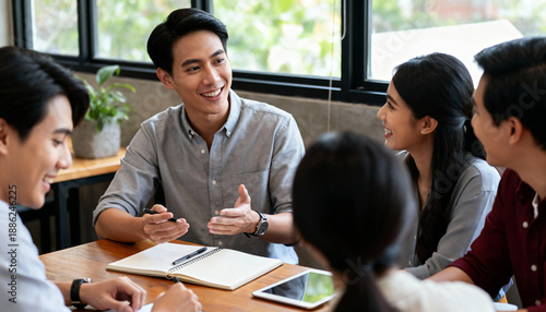 Young asian colleagues discussing ideas in bright office with smiles and positive energy
