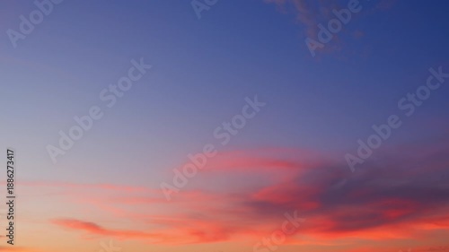 A serene sunset sky timelapse video with soft pink and orange clouds drifting across a deepening blue and purple sky, showcasing gentle cloud motion and the peaceful transition from day to evening.
