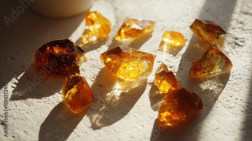 Raw amber or resin pieces on a textured surface with sunlight and shadows