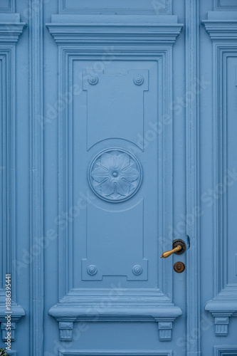 Classic light blue wooden door with ornate panels and gold handle detail