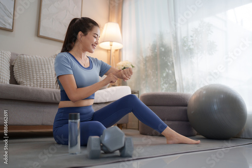 Woman checking smartwatch during indoor home exercise