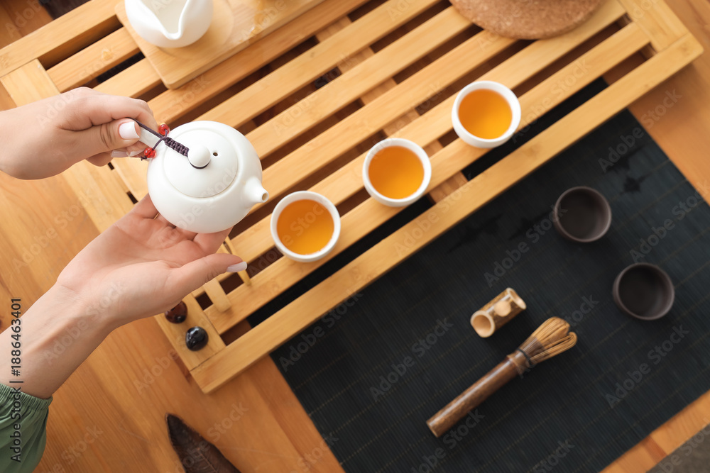 Obraz premium Female hands pouring black tea on table, top view