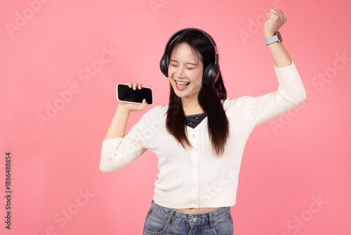Happy Thai smiling confident A woman is holding a cell phone and smiling while wearing headphones
