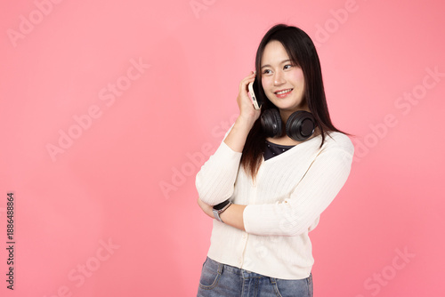Happy Thai smiling confident A woman is talking on her cell phone while wearing headphones