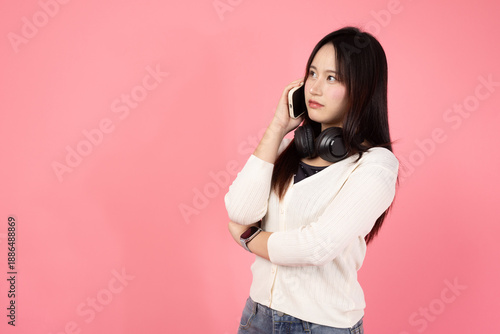 Happy smiling confident A woman wearing headphones and a white sweater is talking on her cell phone