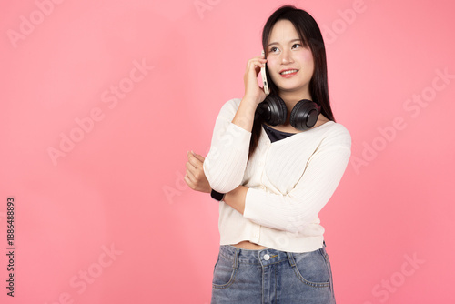 Happy Thai smiling confident A woman is talking on her cell phone while wearing headphones
