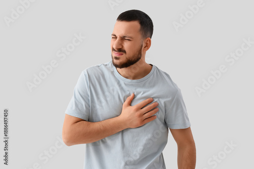 Young man suffering from chest pain on white background