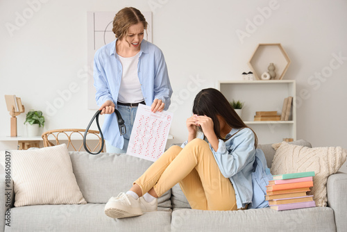Obraz na płótnie Angry mother with results of school test and belt scolding her daughter at home