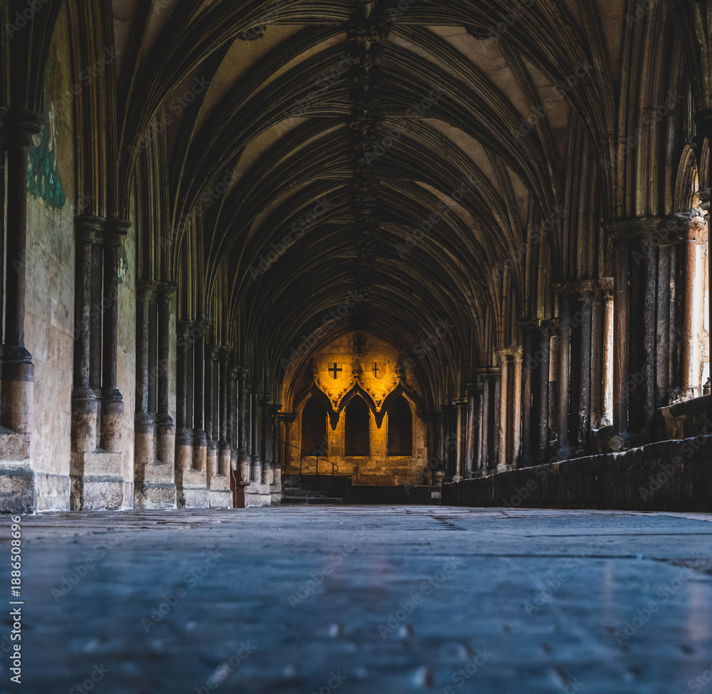 Obraz premium Low angle photo of the cloisters at Norwich Cathedral showing arches, flagstones and subdued lighting