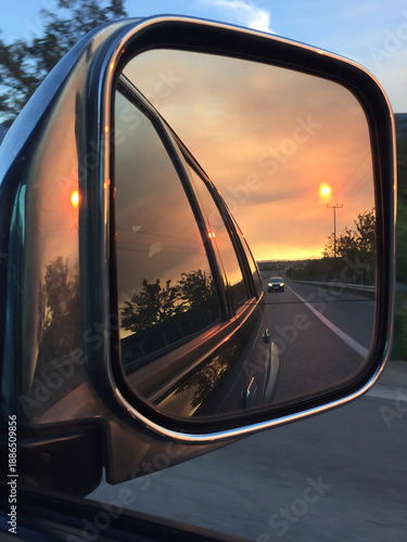 Canvastavla Rearview mirror reflecting a vibrant golden hour sunset over a highway during an