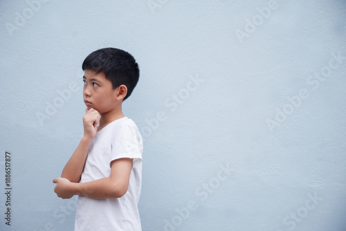 The boy is deep in thought, against a gray background with space for text.