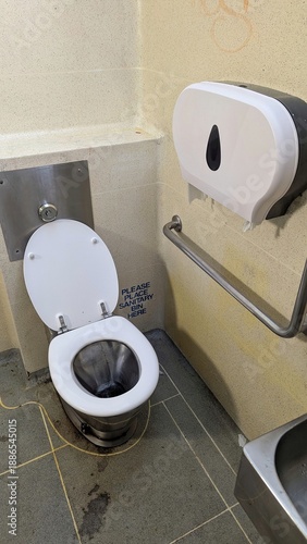 Boring looking public toilet lavatory WC with toilet paper holder and handrail in beige cream color