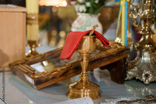 Принти на полотні Golden Chalice with Red Cloth on Church Altar Amidst Ornate Religious Objects an