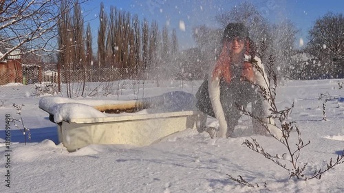 A young girl is outdoors emotionally throwing snow up, creating a dynamic winter shot with sunlight, movement and a sense of freedom.