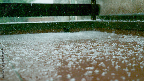 CLOSE UP, DOF: Grains of graupel and rainwater cover the brown tiled balcony.