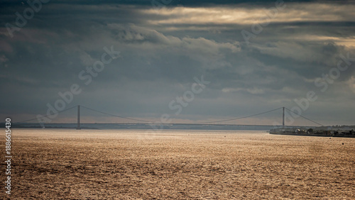 Humber Bridge spanning Humber Estuary under dramatic cloudy sky