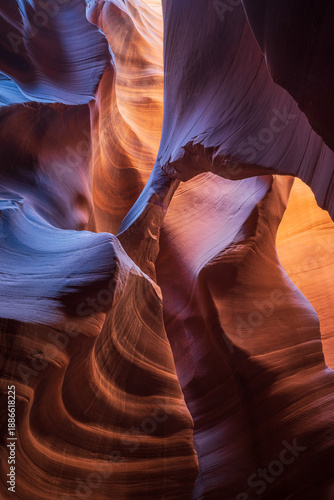 View of swirling sandstone walls carved by time and light, where cool blues meet warm oranges in a dance of shadows and textures, Escalante, Utah, United States.