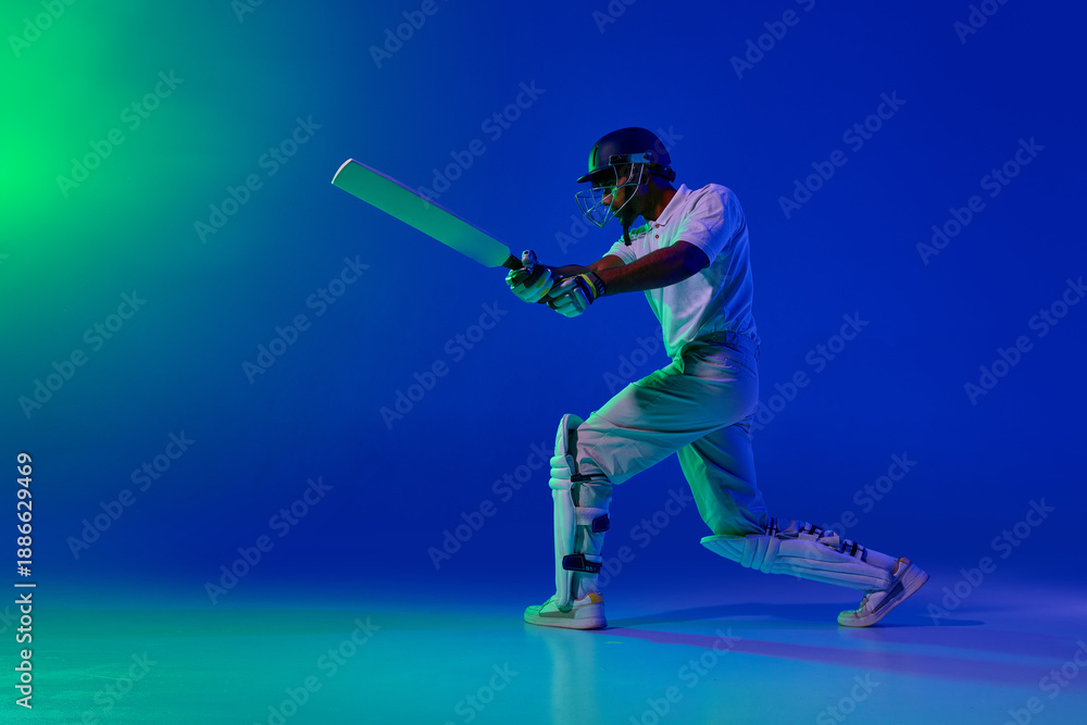 Fototapeta premium Cricket batsman forward attacking shot under blue green studio light. Concept of batting power training, motion control drills, professional cricket coaching content, dynamic sports advertising visual