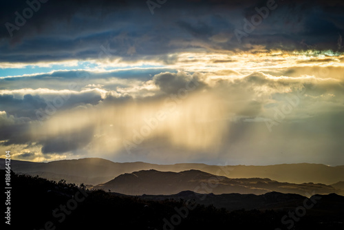 Layers of Scottish mountains with sun rays breaking through clouds