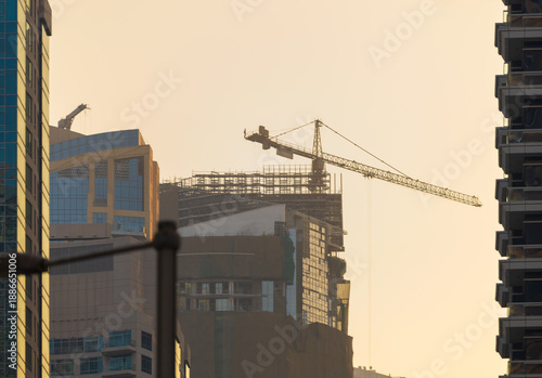 Evening view of the city. Orange sunlight, skyscrapers, buildings, and city streets. On the streets of the Emirates, in a public space.