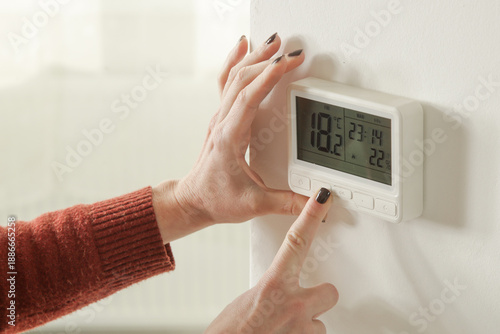 Woman Adjusting Programmable Thermostat for Home Heating and Cooling Control, Close Up