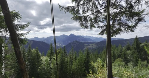 A swing on a cliff in the middle of the forest, in a picturesque landscape