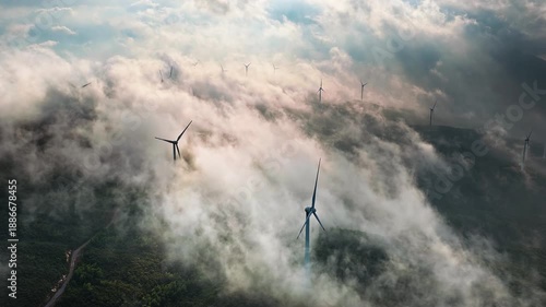 Aerial shot of many wind turbines on a misty mountain ridge generating green energy in the morning