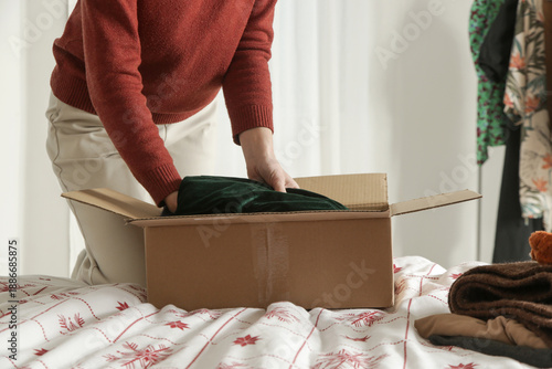 Spring Cleaning Organization, Decluttering, Moving and Donation Concept  Woman Sorting and Packing Clothes into Cardboard Box at Home