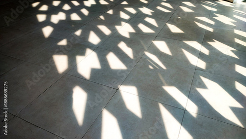 Abstract Islamic background featuring sunlight filtering through a patterned screen, casting geometric shadows on a tiled floor. Minimalist and serene, perfect for Ramadan or Islamic design concepts