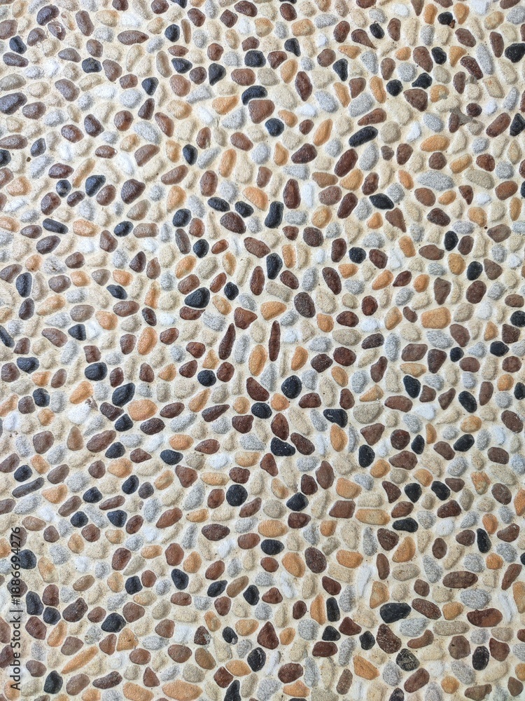 Fototapeta premium Decorative pebble stone floor with rounded natural stones in tan, brown, grey, and black tones, creating organic textured surface ideal for backgrounds, landscaping, and architectural design concepts
