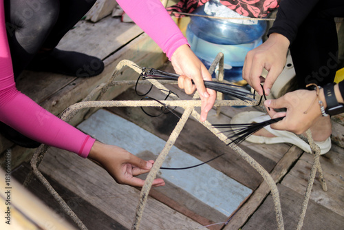 Φωτογραφία Close-up view of hands attaching black cable ties to a spider-shaped metal rebar
