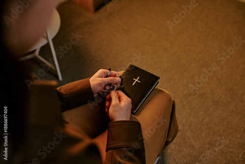 Fotografie Young adult woman holding rosary beads and closed prayer book with cross symbol,