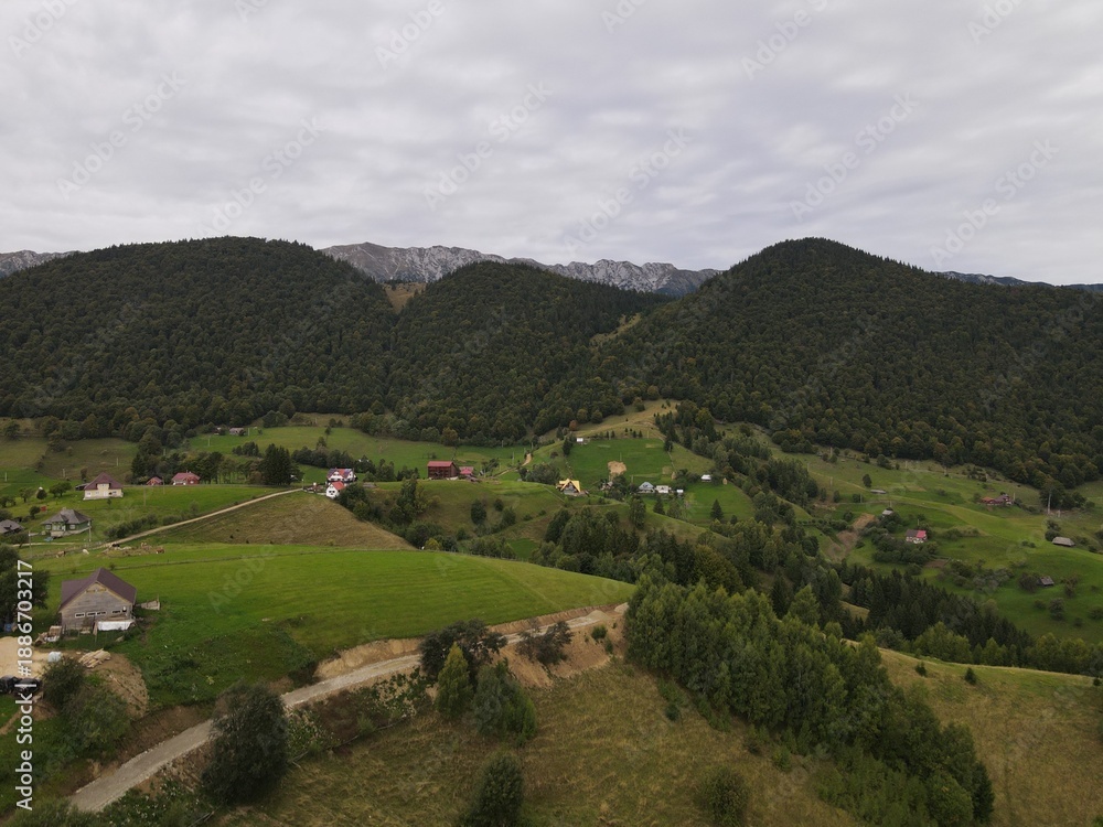 Obraz premium Aerial View of Rural Mountain Village with Forested Hills and Farmland