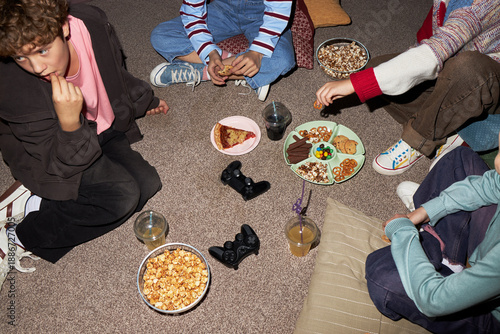 Sticker Group of teenagers sitting on floor eating snacks and drinking juice during casu