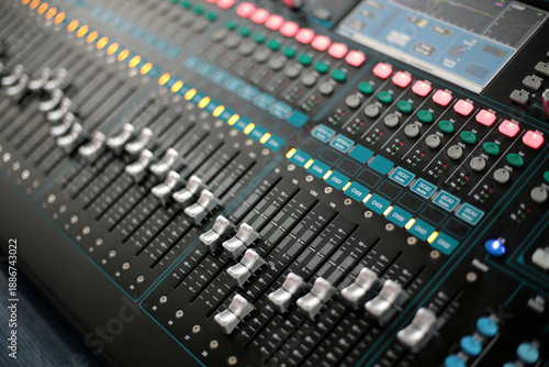 Billede på lærred Close-up view of a modern digital audio mixing console with illuminated faders a