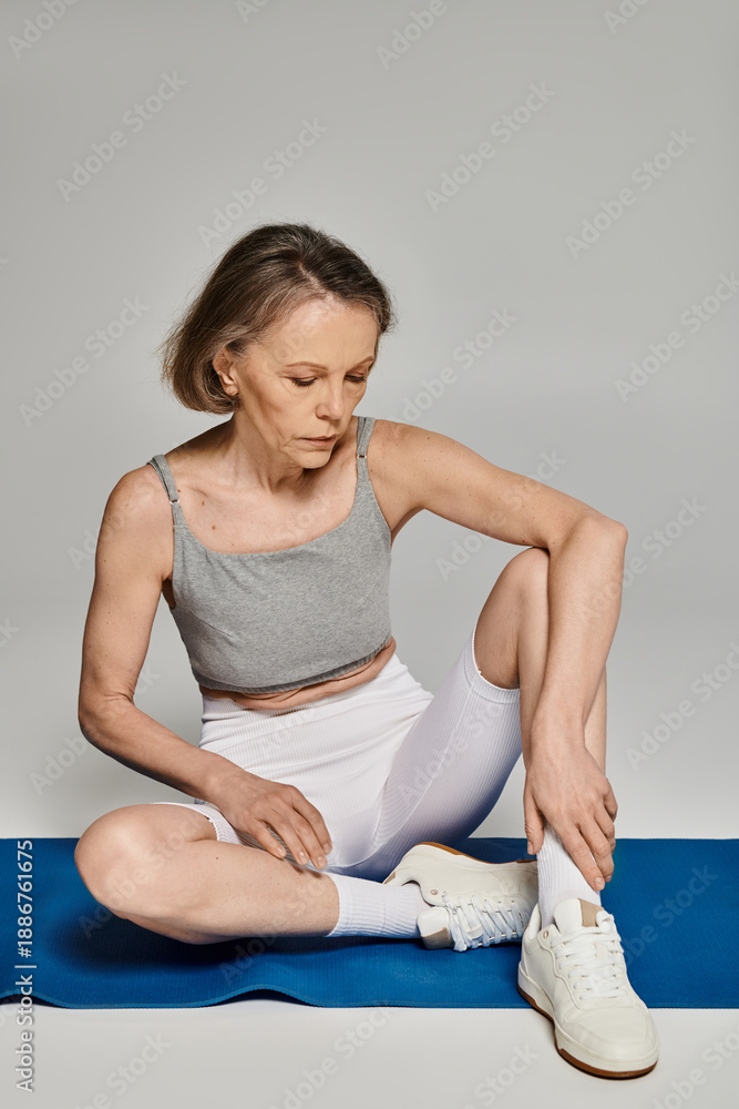 Fototapeta premium Mature woman practicing yoga on mat with focus and grace indoors