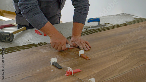 CLOSE UP: Contractor places wedges to seal laid tiles and leave them to dry.