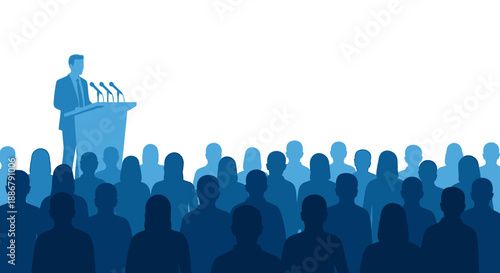 A speaker stands at a podium with microphones addressing a large audience of silhouetted people.