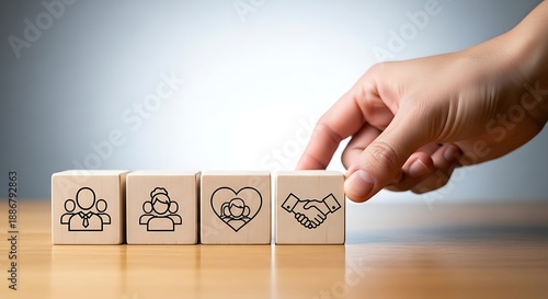Hand touching wooden blocks with icons depicting human relationships, family, love and partnership for building strong community and social bonds.