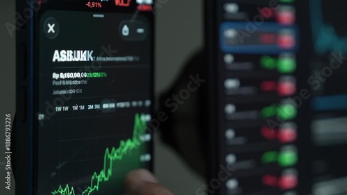 close up smartphone with laptop and open stock exchange, trading Online app interface. Man hand scrolling touch screen analysing chart forex crypto currency.