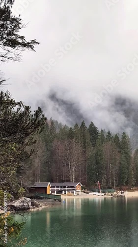 A vertical real-time shot of a lakeside restaurant and boat rental in the Alps.