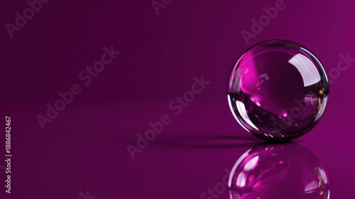 Transparent glass sphere on reflective purple surface.