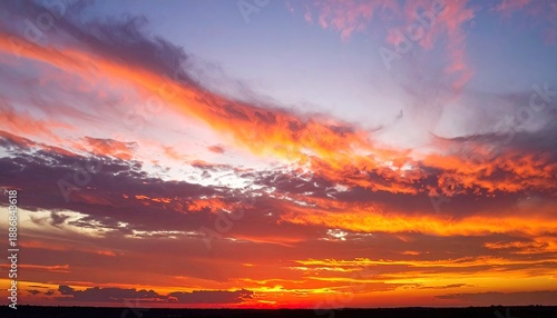 Fiery orange and purple clouds streak across a darkening horizon