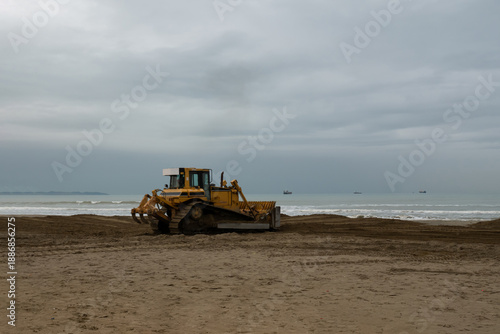 Cuadro en lienzo Bulldozer reshaping sand on coastal beach for restoration under dramatic skies