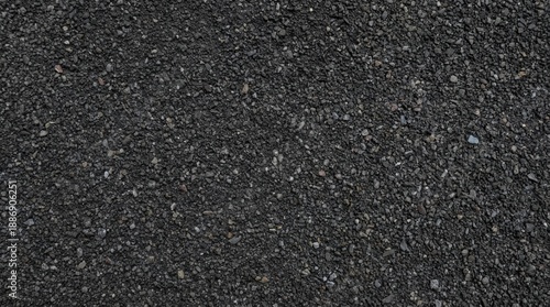 Close-up of a dark grey asphalt road texture, featuring small pebbles and gravel. Ideal for industrial, urban, and construction backgrounds.