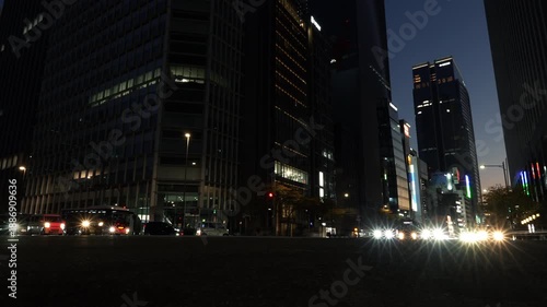Cinematic long exposure of night traffic trails in a Tokyo financial district.